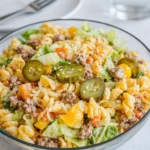 A large bowl of Big Mac Pasta Salad with creamy dressing and sesame seeds.