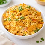 A vibrant Chili Cheese Fritos Corn Salad in a white bowl.