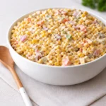A bowl of Creamy Corn Salad on a wooden table