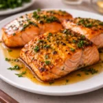 Garlic Butter Honey Baked Salmon fillets on a baking sheet with lemon