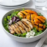 A vibrant bowl of Grilled Peach and Chicken Salad with charred fruit and goat cheese.