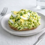 Zesty Avocado Egg Salad in a white bowl with parsley garnish