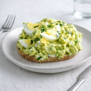 Zesty Avocado Egg Salad in a white bowl with parsley garnish