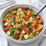 A vibrant Zesty Italian Pasta Salad in a white bowl on a wooden table.