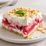 A delicious Layered Rhubarb Pudding Dessert in a glass dish showing colorful layers.
