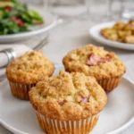 Golden brown Quick Rhubarb Muffins with streusel topping on a wooden rack.