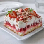 A slice of Strawberry Crunch Poke Cake with pink gelatin filling and strawberry crumble topping.