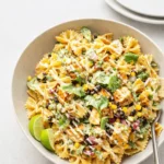 A colorful bowl of Taco Pasta Salad with avocado and lime.